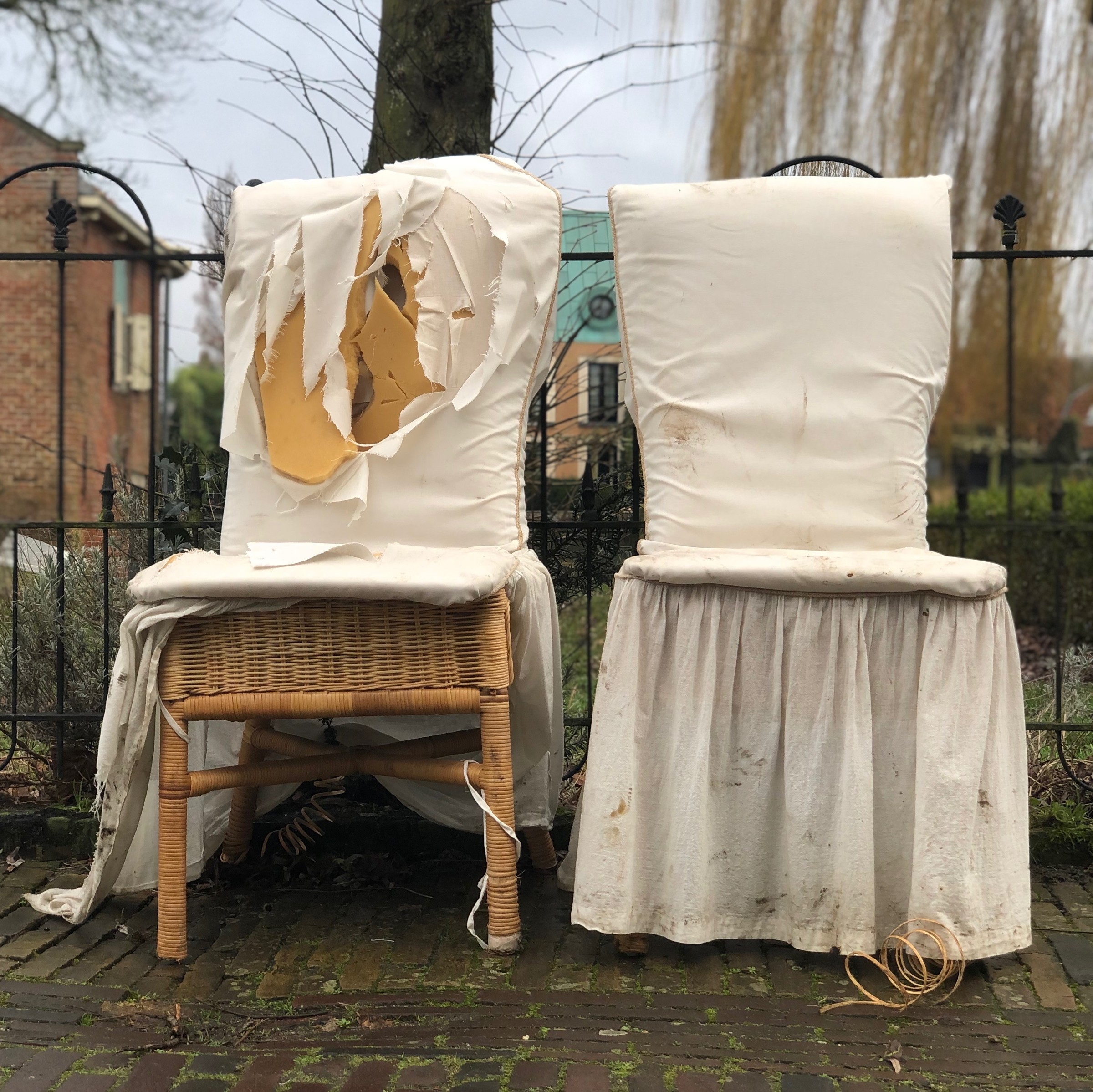 Twee beklede stoelen staan naast elkaar onder een open, verweerd dak.