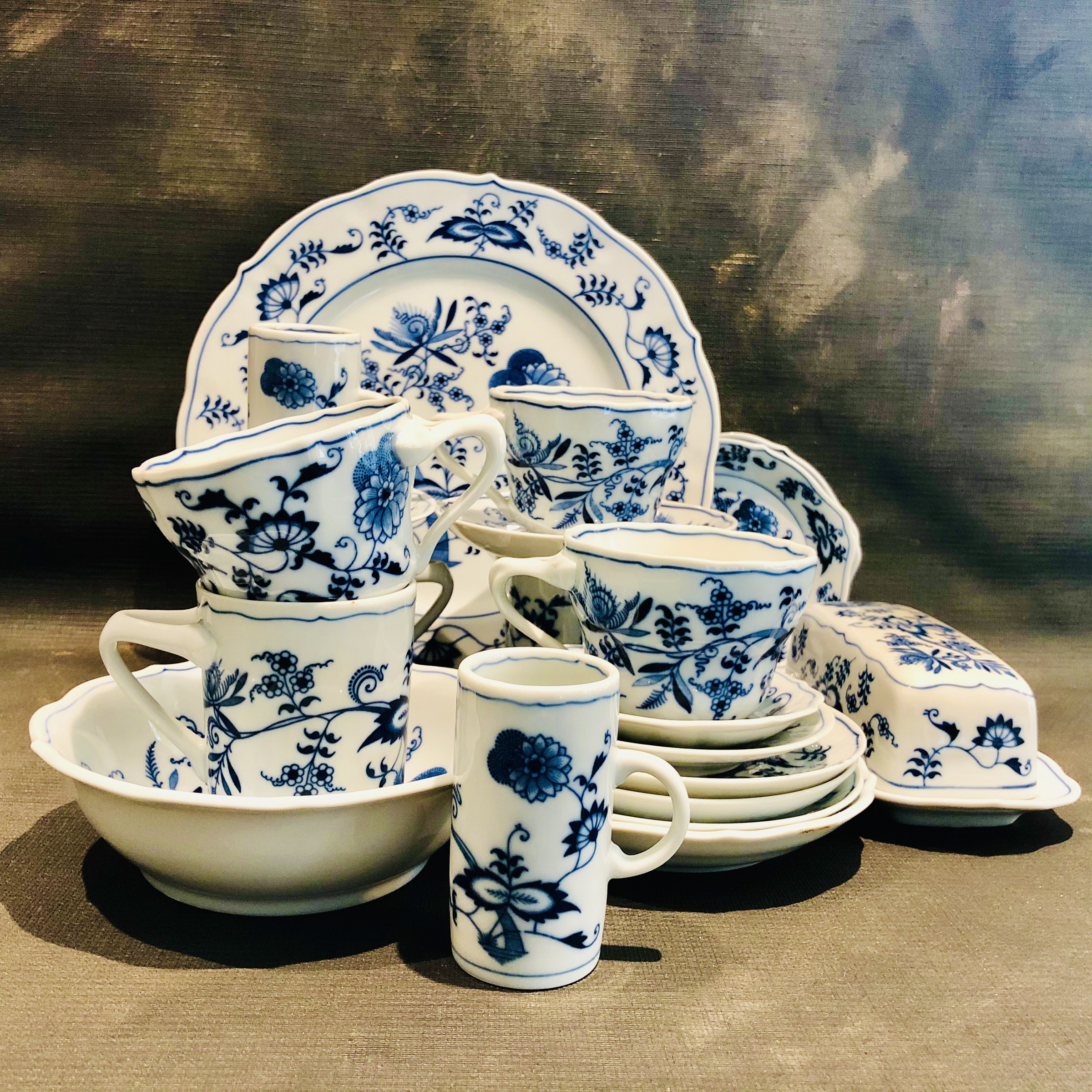 Een stilleven van blauw-wit servies, met borden, kopjes en een koffiepot.