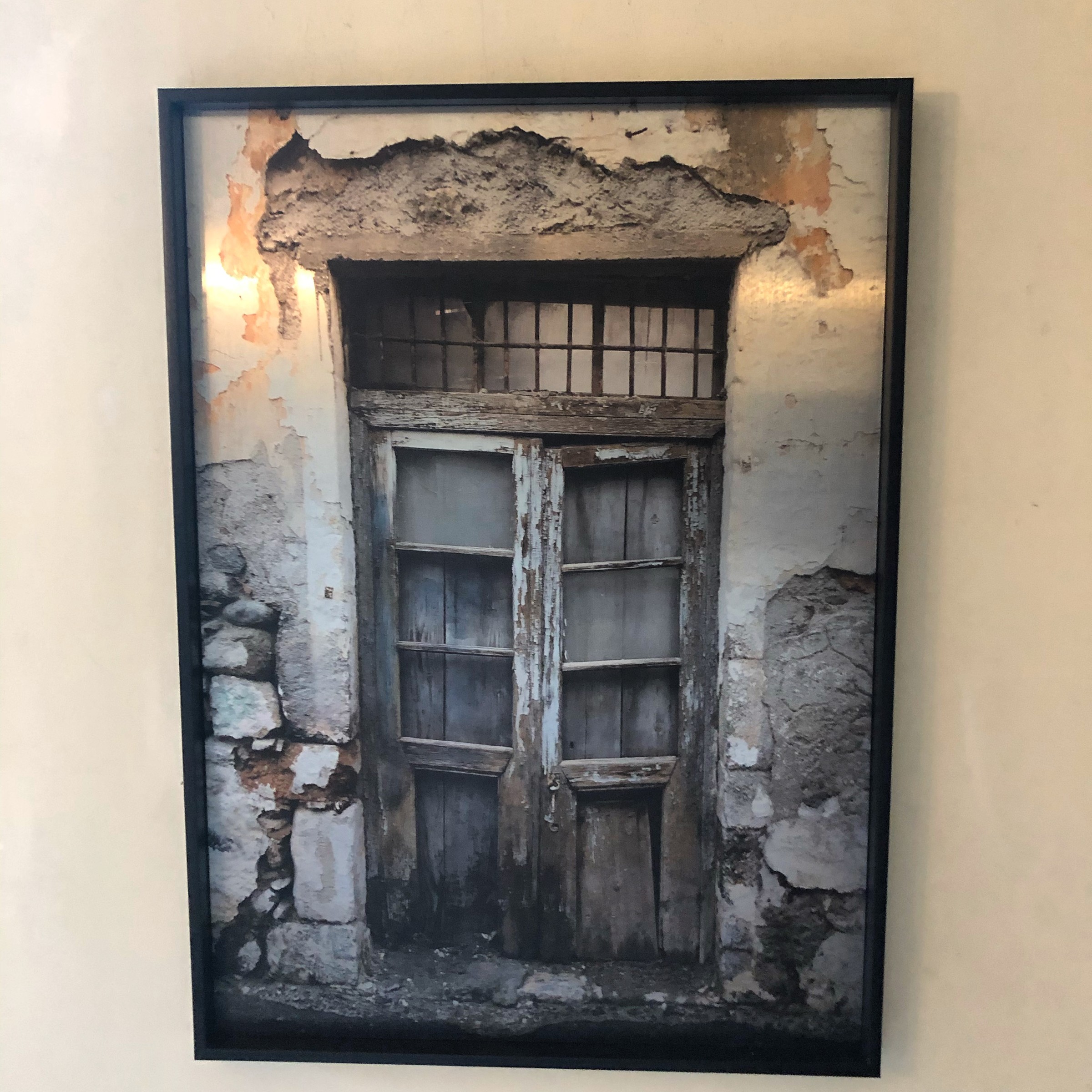 Een ingelijst beeld van een oude houten deur en een door de tijd getekende gevel.